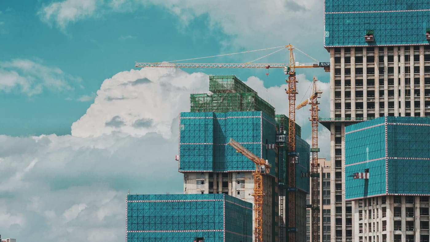 Active commercial high-rise construction with tower cranes and safety netting